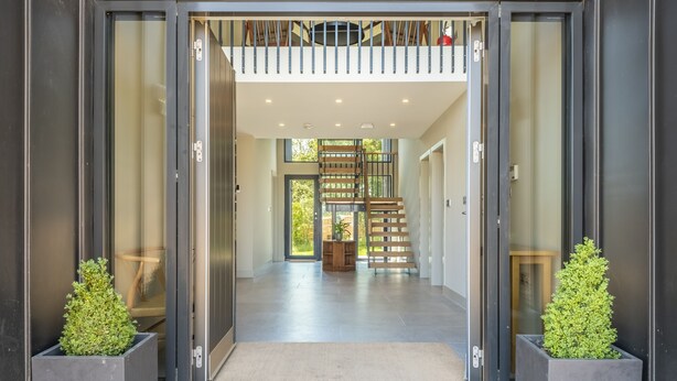 A modern entrance with a glass door, a staircase, and two potted plants. - The Grain Store, Reepham, Norfolk (Reepham)