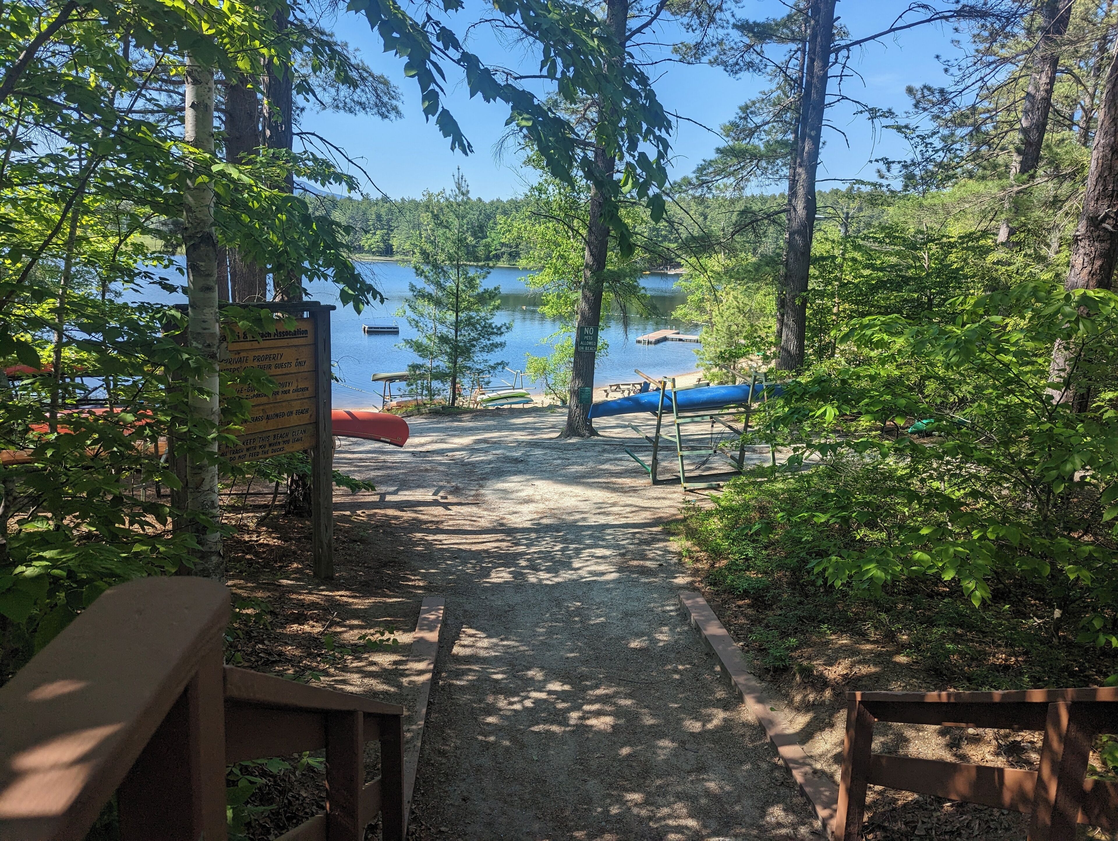 A gravel path leading to a dock with canoes, surrounded by trees and a sign indicating private property.