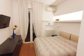 A bedroom with a bed, a dresser, a radiator, and a window with curtains. - Penthouse F8 | Rooftop Terrace, Two Towers View (Bologna)