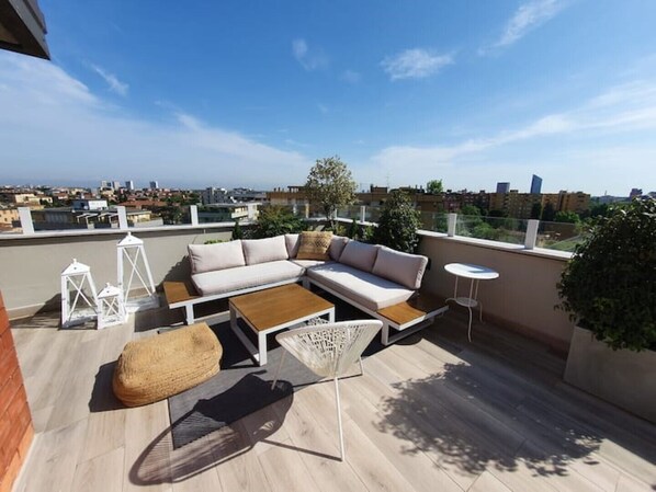 A rooftop terrace with a sectional sofa, a small round table, and a decorative lantern. - Penthouse F8 | Rooftop Terrace, Two Towers View (Bologna)