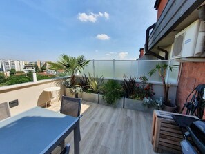 A rooftop terrace with a table and chairs, potted plants, and a view of the cityscape. - Penthouse F8 | Rooftop Terrace, Two Towers View (Bologna)
