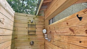 Una cabaña de madera con puerta de madera, una ventana pequeña y un gancho de metal en la pared.