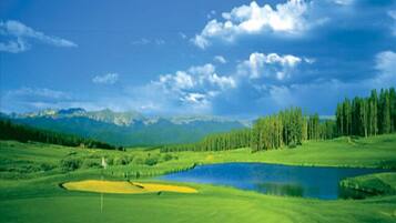 Scenic golf course situated on the property grounds, surrounded by rolling hills, forests, and mountain terrain under open skies.