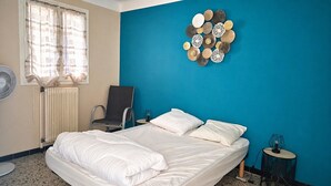 Ein Hotelzimmer mit Bett, Stuhl, Tisch, Wanduhr und Heizkörper.