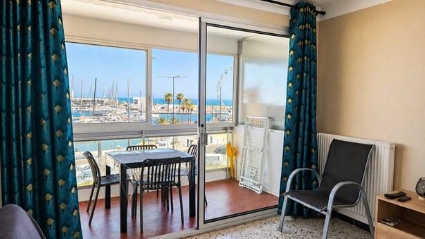 Ein Balkon mit Tisch und Stühlen, einer Heizung und Blick auf den Yachthafen.