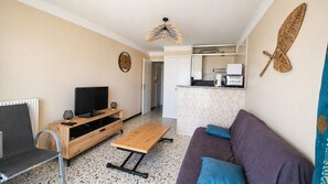 A compact living space with a TV, wooden entertainment unit, a sofa, a coffee machine, and a kitchenette. - One Bedroom apartement with sea and marina view (Canet-en-Roussillon)