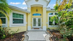 A two-story house with a yellow facade, white trim, and a front porch. - Shared Dock and Private Backyard with Pool -Casa Mango (Sarasota)