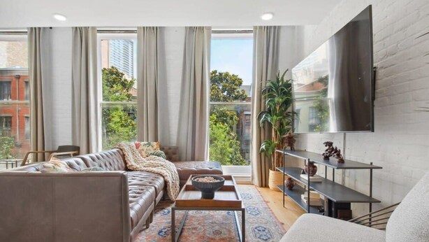 A modern living room with a leather sofa, a coffee table, and a TV mounted on the wall.
