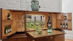 A bar area with shelves of bottles, glasses, and a decorative vase.