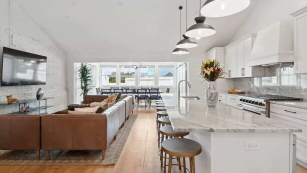 A modern kitchen with a central island, pendant lighting, and a view to the dining area.