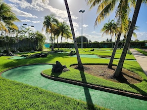 Um campo de golfe bem cuidado, com fairways verdes, bunkers de areia e céu claro.