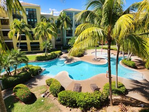 Un complexe hôtelier doté d’une piscine, de palmiers et d’un bâtiment à plusieurs étages.