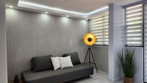 A modern living room with a grey sofa, a floor lamp, and a potted plant. - Aquatika Minimalist Beach Escape (Loiza)