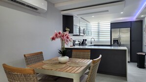 A modern kitchen with a central island, white cabinetry, and a stainless steel refrigerator. - Aquatika Minimalist Beach Escape (Loiza)