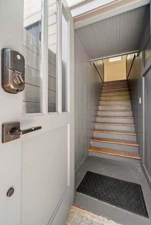 Un escalier étroit doté d’une rampe métallique et d’un tapis noir au bas.