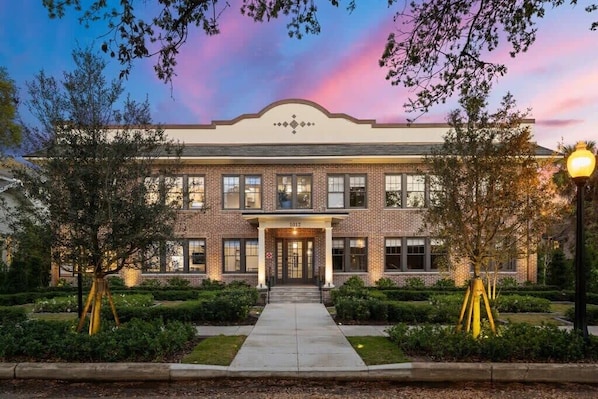 A brick building with a symmetrical facade, large windows, and a central entrance.