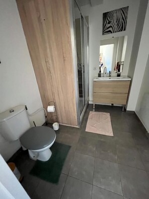 A modern bathroom with a toilet, sink, and mirror. - Maison Cheptainville Proche Ferme de la Doudou (Cheptainville)
