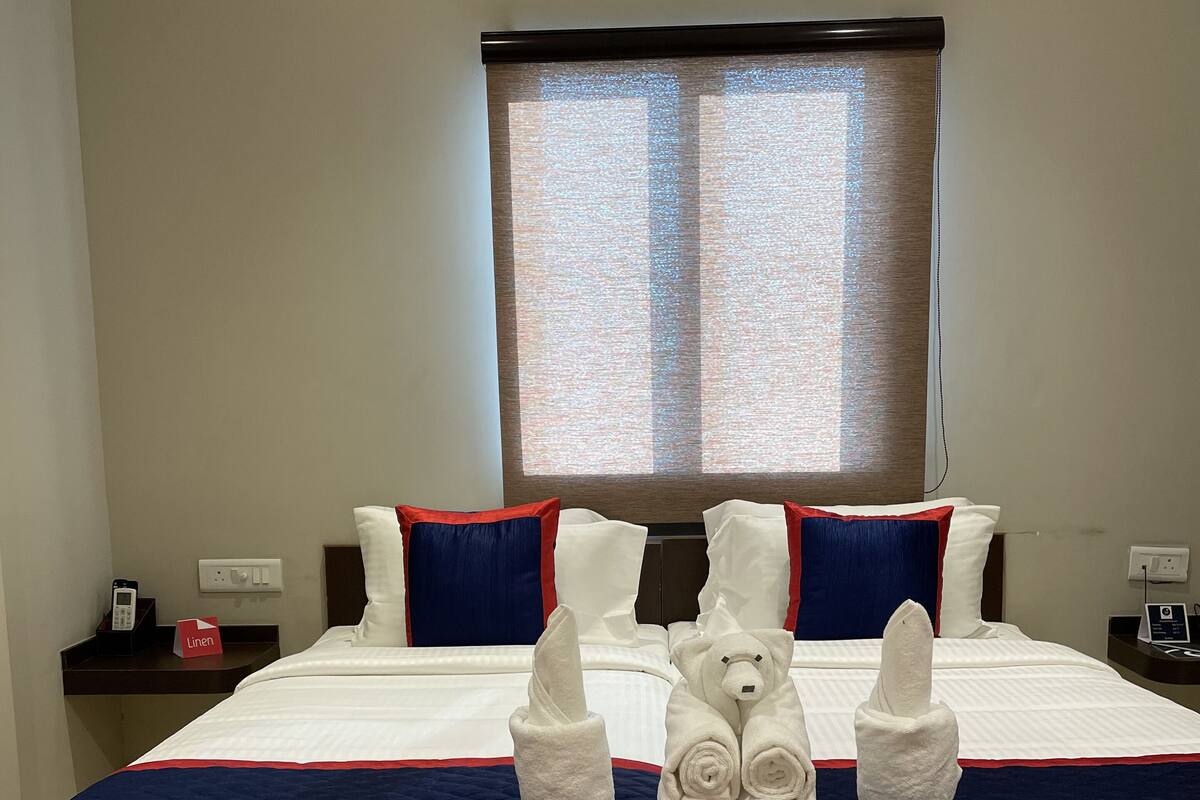 A double bed with white linens, a blue and red striped bedspread, and two white towels folded in a bear shape.