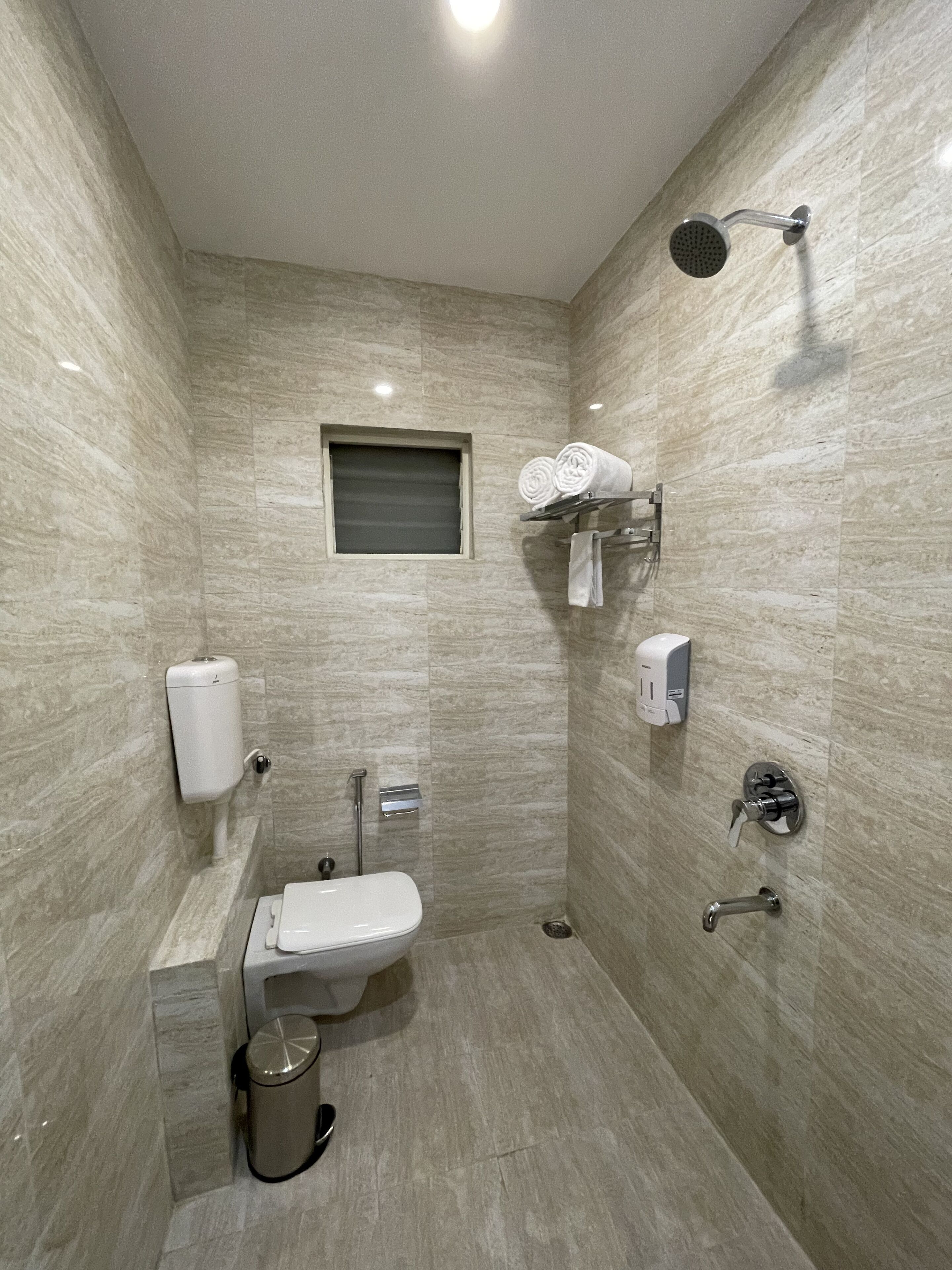 A modern bathroom with a toilet, bidet, hand dryer, and towel rack.