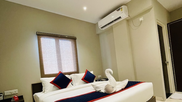 A hotel room with a large bed, a window, an air conditioning unit, and a bedside table with a phone and a red object. - Zip By Spree Hotels Bhopal (Bhopal)