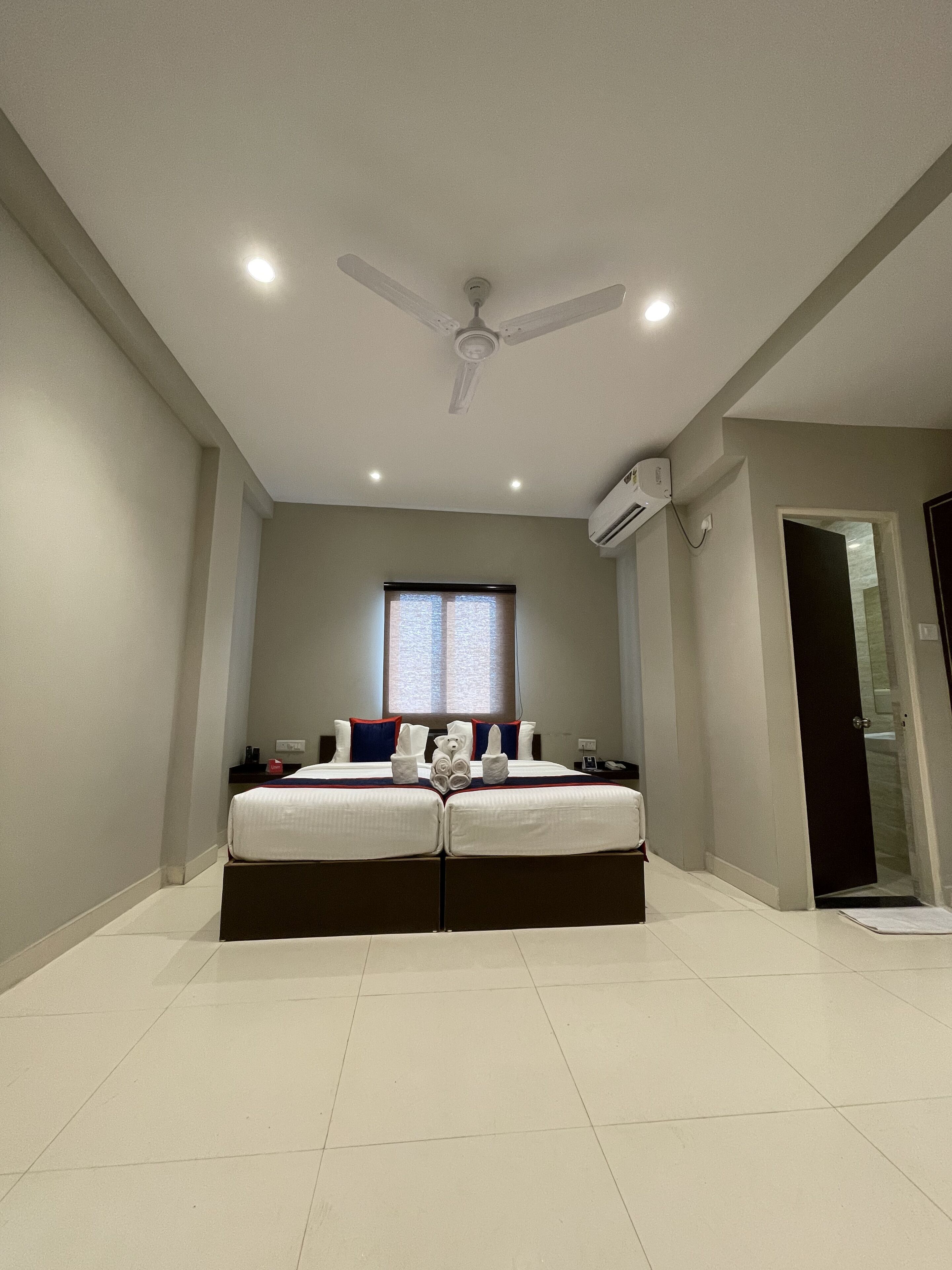 A modern bedroom with a large bed, a ceiling fan, and a window with blinds.