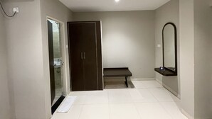 A bathroom with a dark door, a bench, a mirror, and a tiled floor. - Zip By Spree Hotels Bhopal (Bhopal)