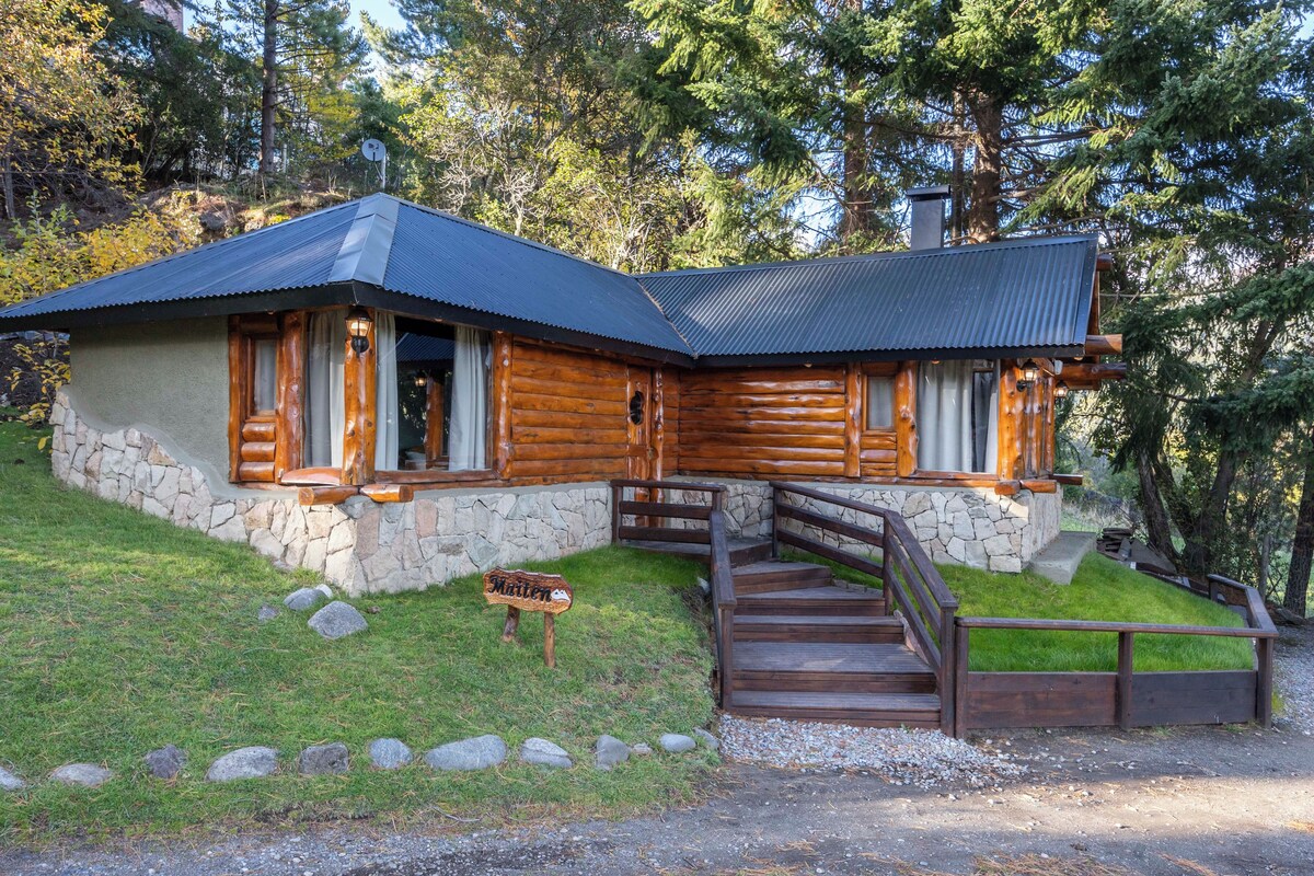 Une cabane en rondins, avec des fondations en pierre, un revêtement extérieur en bois et un toit en métal.
