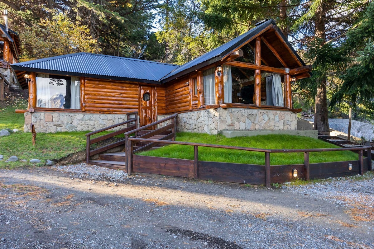 Une cabane en rondins, avec des fondations en pierre, un revêtement extérieur en bois et un toit en métal.