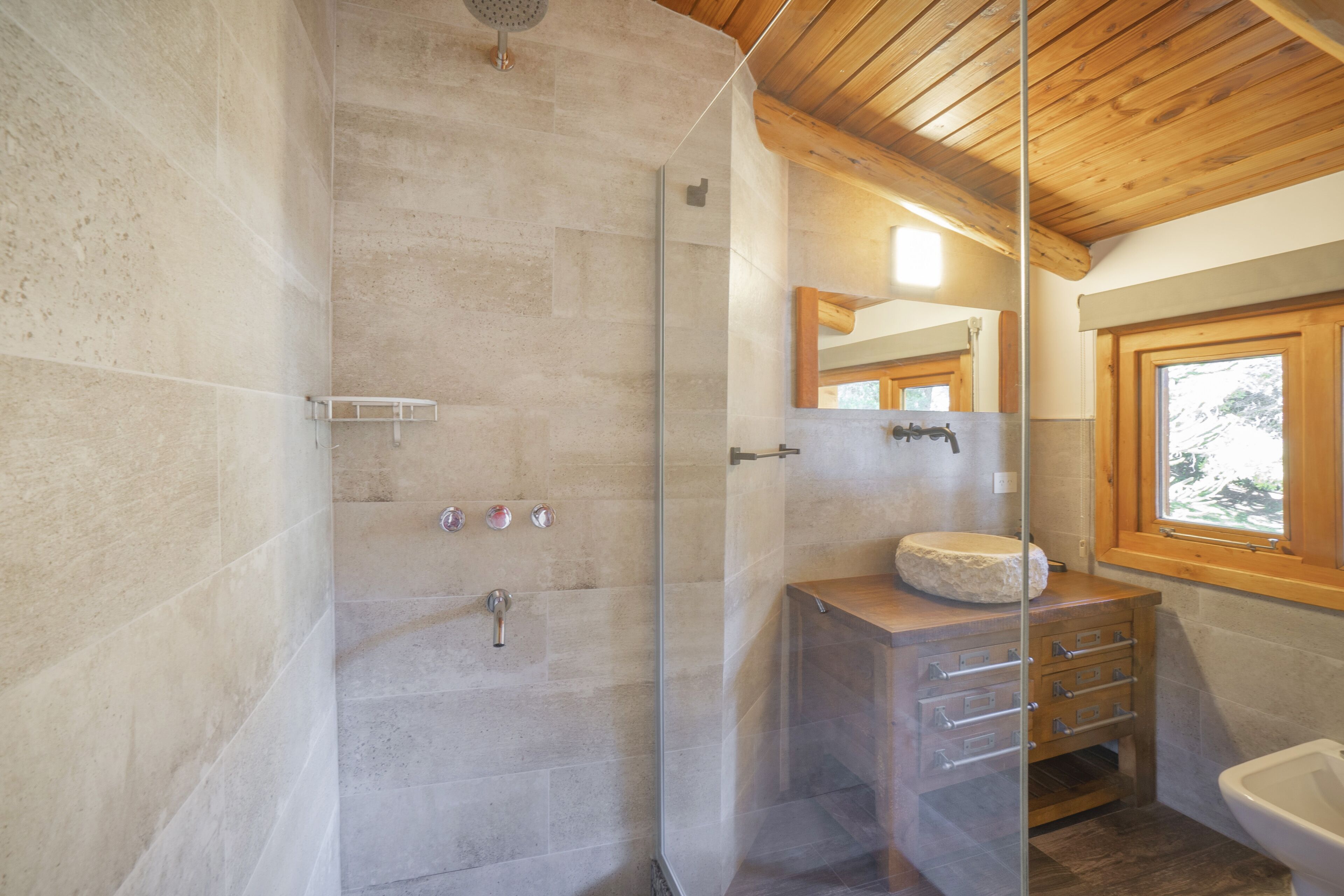 Een moderne badkamer met een douchecabine van glas, een houten wastafelmeubel en een grote spiegel.