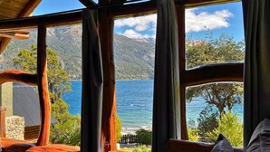 A cabin with a large window overlooking a lake and mountains. - Villa Labrador Bariloche (San Carlos de Bariloche)