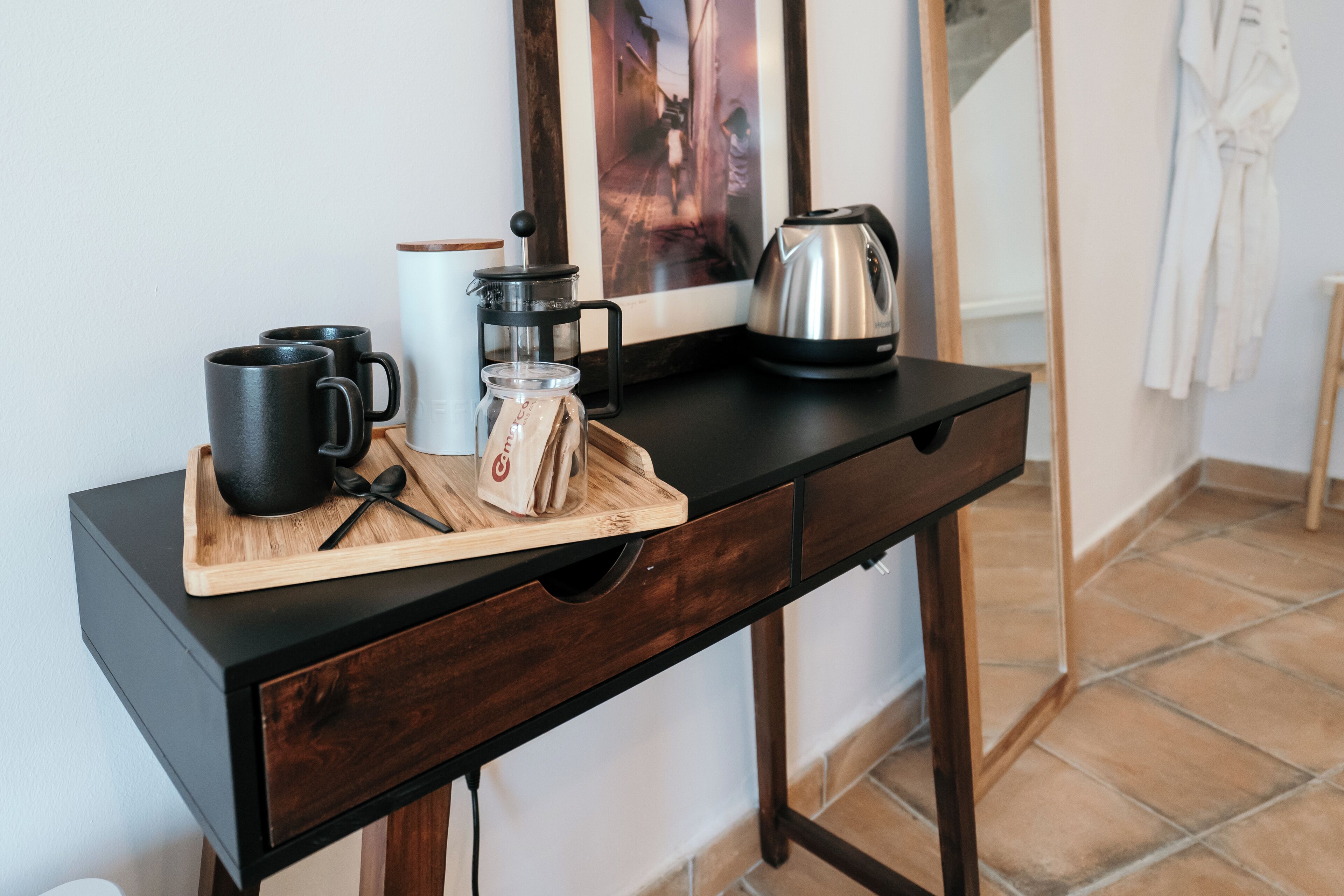 A kitchen counter with a coffee maker, a kettle, and a tray with coffee cups and a bag of coffee beans.