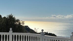 Une piscine bordée d’une balustrade blanche, entourée de verdure et donnant sur une étendue d’eau.