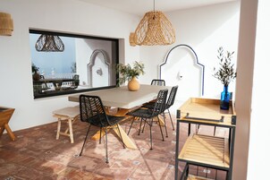 Un espace repas doté d’une grande fenêtre, de luminaires suspendus en osier et offrant une vue sur l’extérieur.