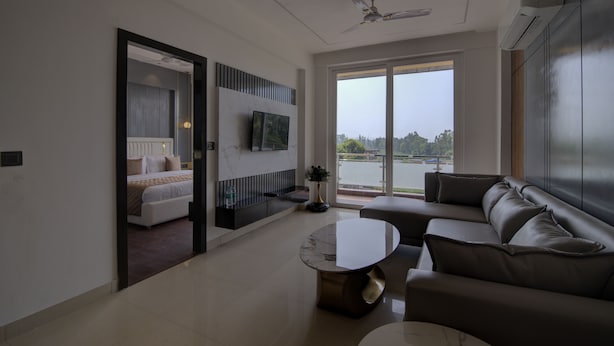 A modern living room with a sofa, a coffee table, and a TV mounted on the wall. - Comfort Inn Karnal (Nilokheri)
