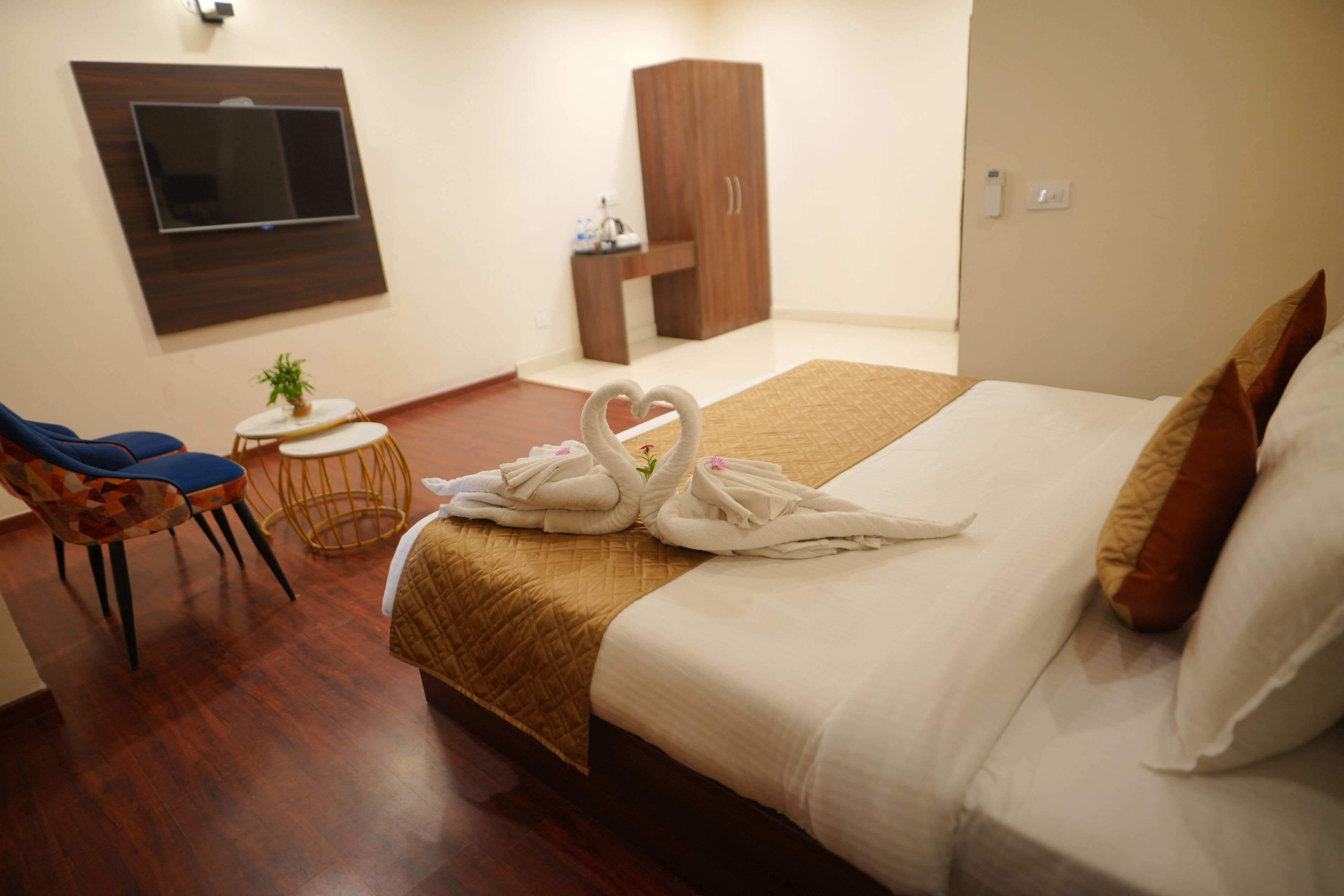 Une chambre d’hôtel avec un lit, un téléviseur fixé au mur, une armoire, une petite table avec une plante et une chaise.