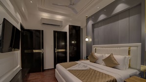 A modern hotel room with a large bed, a ceiling fan, an air conditioning unit, and a flat-screen TV mounted on the wall. - Comfort Inn Karnal (Nilokheri)