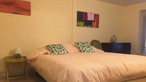 Ett sovrum med en säng, kuddar, ett nattduksbord och en grön matta.