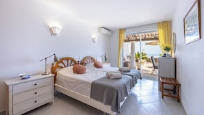 Quarto com duas camas, uma mesa de cabeceira, escrivaninha e vista para o exterior.