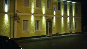 A yellow building with multiple windows and a door, illuminated by exterior lights. - Apartment Graz center (Graz)