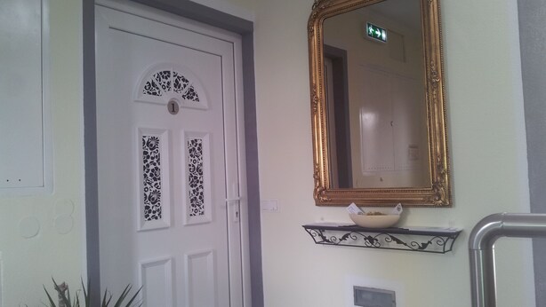 A white door with a decorative panel and a gold-framed mirror above it. - Apartment Graz center (Graz)