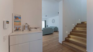 Ein modernes Wohnzimmer mit Treppe, einer Couch und einer Wanduhr.
