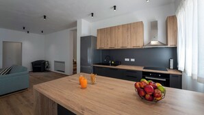 Eine moderne Küche mit Holzschränken, einem Einbauofen und einer Arbeitsplatte mit Obstschale und Orangensaft.