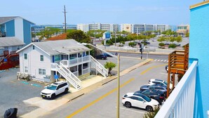 A coastal hotel with a white exterior, a balcony, and a staircase leading to the entrance.