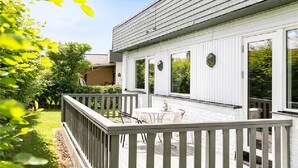 Un bâtiment blanc doté d’une terrasse en bois et d’une petite table.