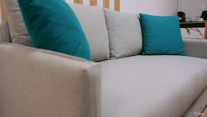 A grey sofa with teal cushions.