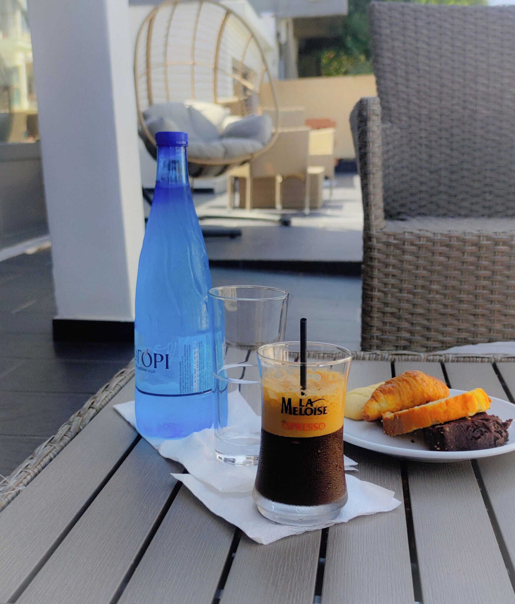 A table with a beverage, a bottle, and a plate of food.