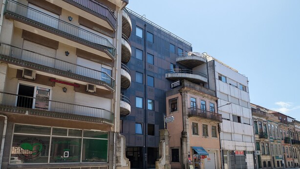 Un immeuble à plusieurs étages doté de balcons, de grandes fenêtres et d’une devanture avec une enseigne.