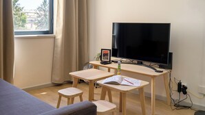 Un salon moderne doté d’un grand téléviseur à écran plat, de meubles en bois et offrant une vue par une fenêtre.