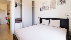 Une chambre à coucher comprenant un lit, une armoire et un mur orné de trois tableaux encadrés.