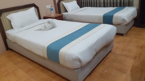 Two twin beds with white bedding and blue stripes, a wooden floor, and a window with curtains. - Centrally located at west Thamel quite Location 5 stories Apartment  (Kathmandu)